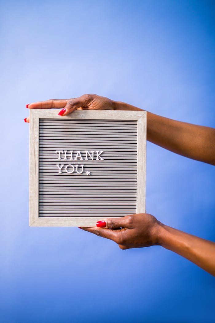about-02 Hands holding thank you sign on blue backdrop, perfect for social media and digital marketing.